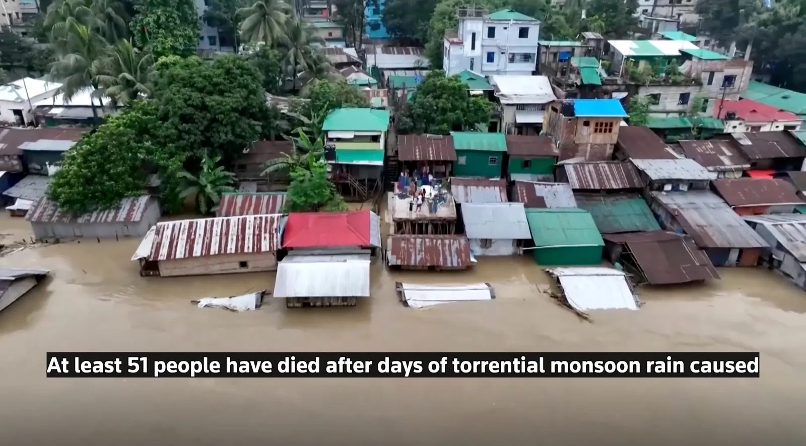 Rows of homes stand partially submerged in muddy floodwater in Bangladesh