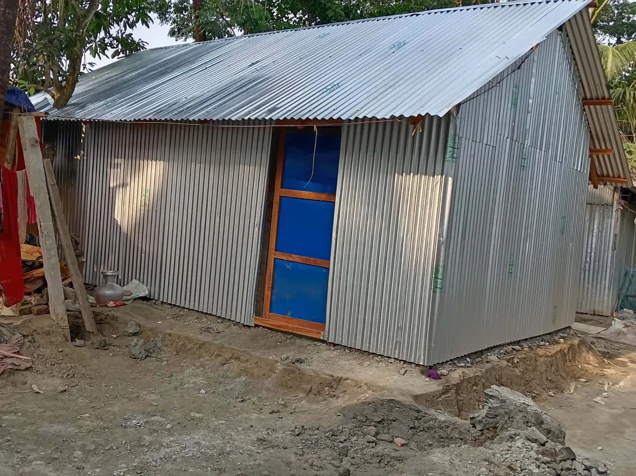 The completed corrugated-metal home with a secure door and roof